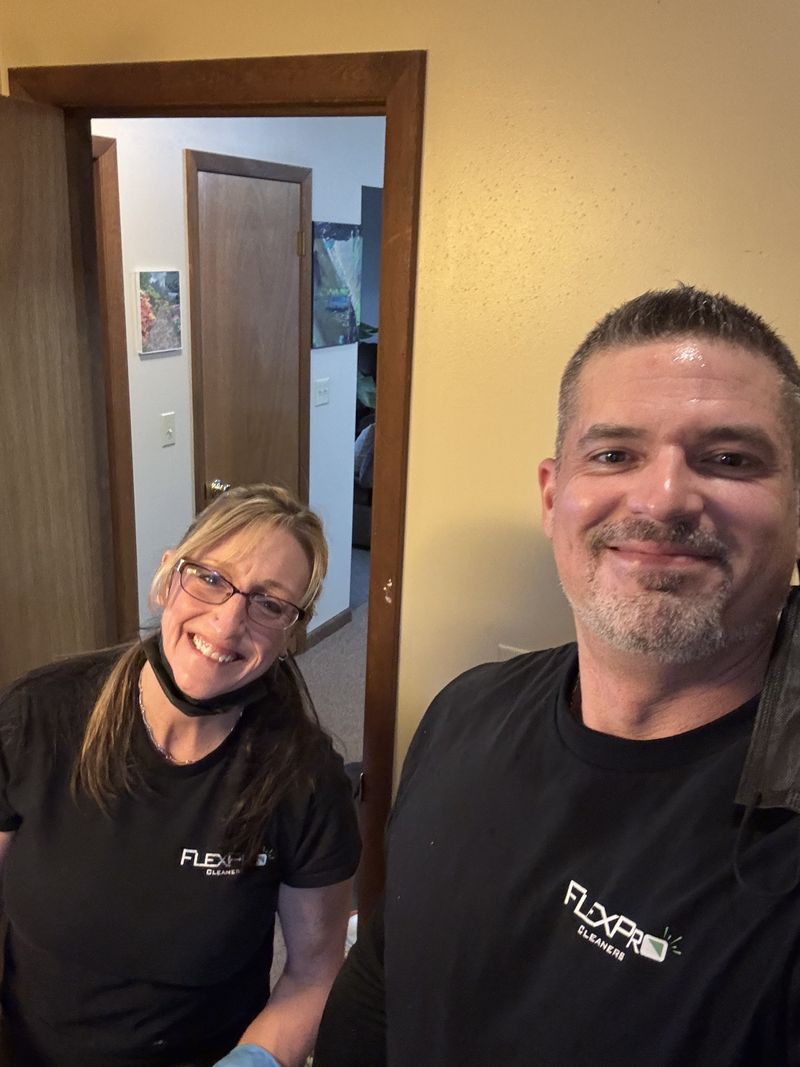Two FlexPro team members in black FlexPro shirts smiling in a hallway