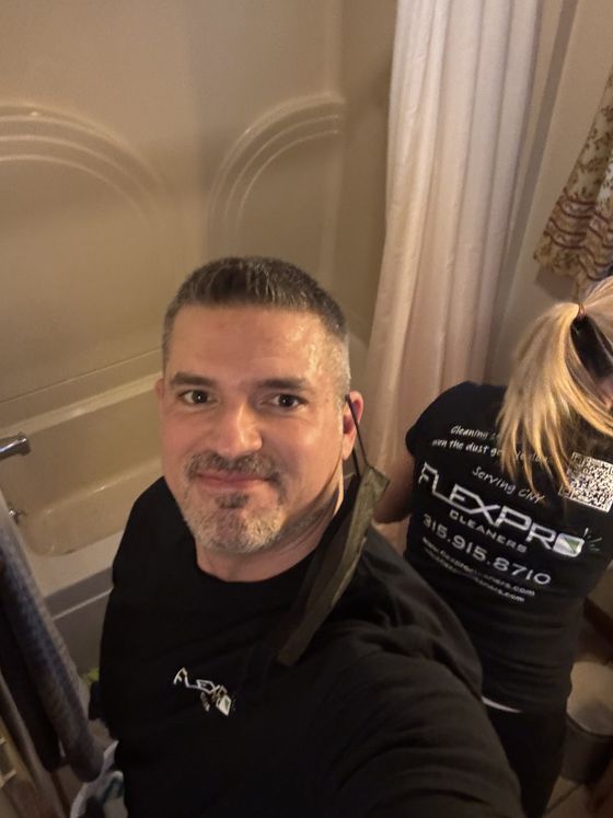 A FlexPro team member on the job in a client's bathroom, with a colleague cleaning behind him